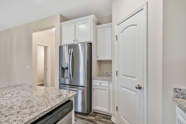 kitchen with light stone countertops, white cabinetry, appliances with stainless steel finishes, and dark wood-type flooring