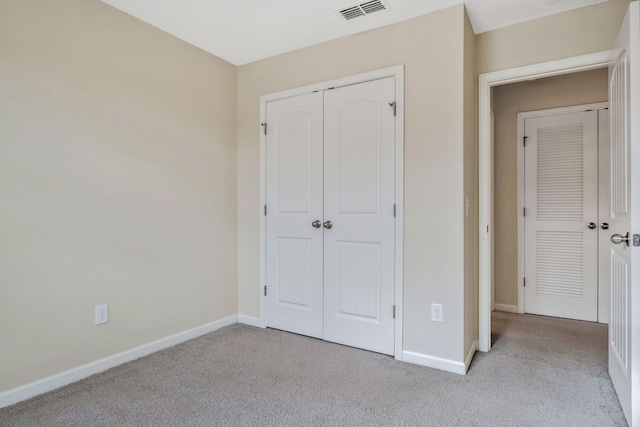 unfurnished bedroom with light colored carpet and a closet