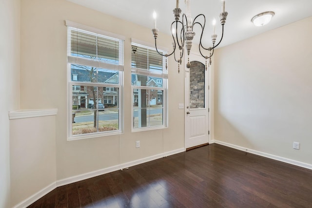 unfurnished dining area featuring dark wood-type flooring and a notable chandelier