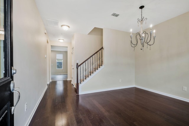 foyer entrance with an inviting chandelier and dark hardwood / wood-style floors