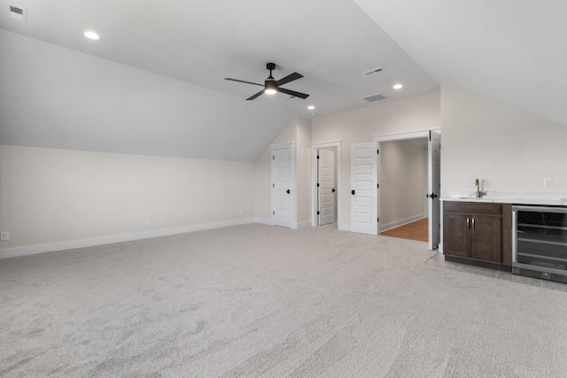 additional living space featuring lofted ceiling, indoor wet bar, ceiling fan, light colored carpet, and beverage cooler