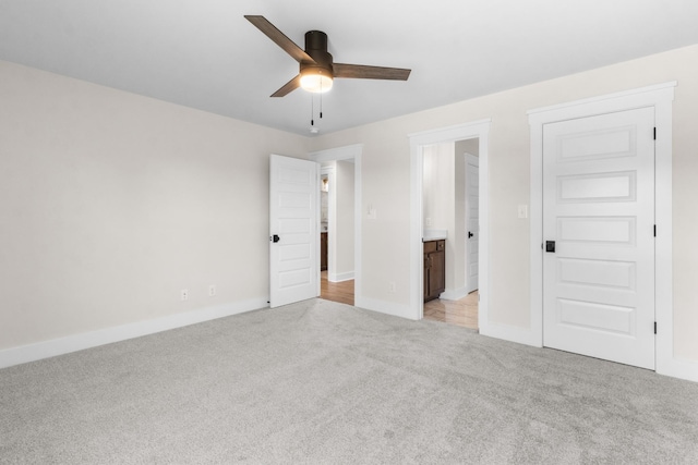 unfurnished bedroom with ensuite bathroom, light colored carpet, and ceiling fan