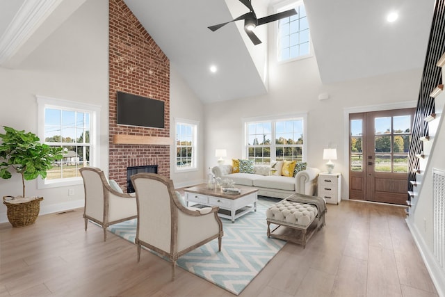 living room with a fireplace, high vaulted ceiling, ceiling fan, and light wood-type flooring