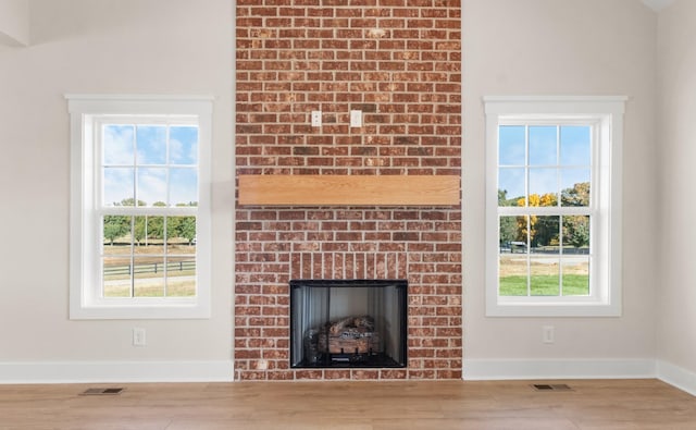 unfurnished living room with wood-type flooring and a brick fireplace