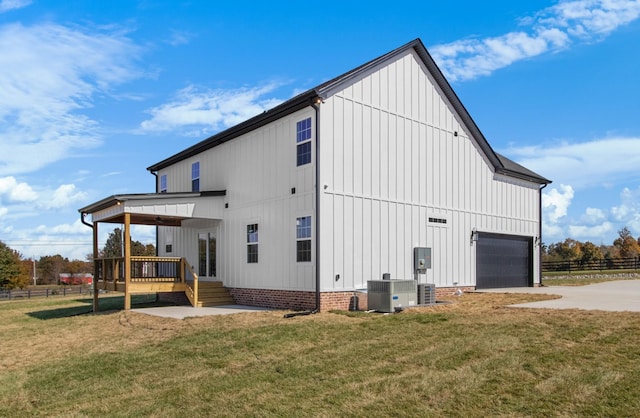 rear view of house featuring cooling unit, a yard, a wooden deck, and a garage