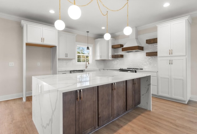 kitchen with a kitchen island, white cabinetry, custom exhaust hood, hanging light fixtures, and light stone counters