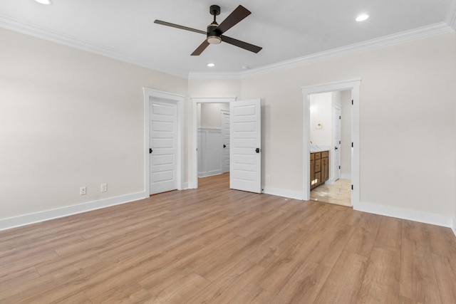 unfurnished bedroom with ensuite bath, a spacious closet, light wood-type flooring, ornamental molding, and ceiling fan