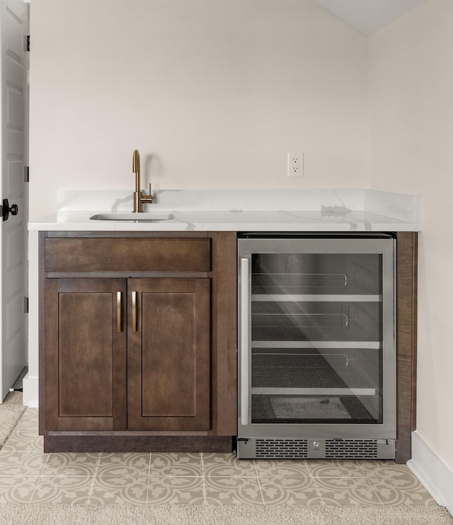 bar with beverage cooler, sink, and dark brown cabinets