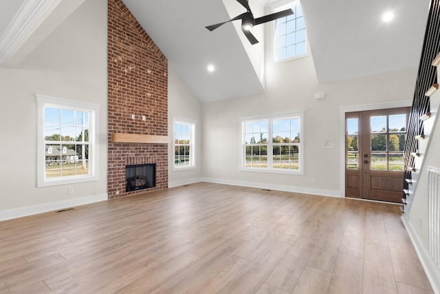 unfurnished living room featuring ceiling fan, high vaulted ceiling, light hardwood / wood-style floors, and a brick fireplace