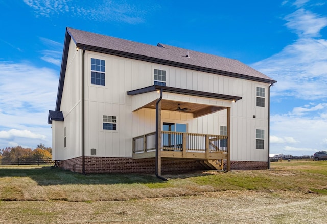 rear view of property featuring ceiling fan and a yard