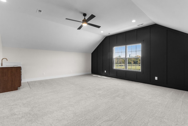 additional living space with light carpet, sink, vaulted ceiling, and ceiling fan