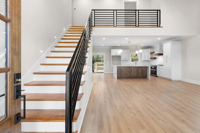 staircase with a high ceiling, wood-type flooring, and ornamental molding