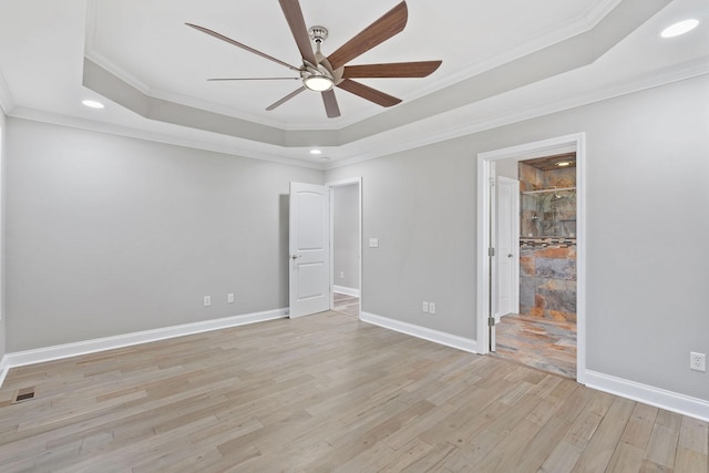 spare room featuring a raised ceiling, ornamental molding, ceiling fan, and light hardwood / wood-style flooring