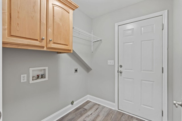 clothes washing area with electric dryer hookup, washer hookup, hardwood / wood-style flooring, and cabinets