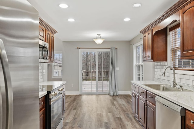 kitchen featuring stainless steel appliances, sink, light wood-type flooring, and decorative backsplash