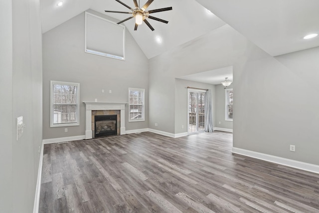 unfurnished living room featuring high vaulted ceiling, plenty of natural light, a tiled fireplace, and hardwood / wood-style floors