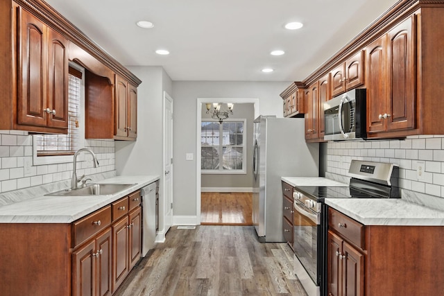 kitchen with stainless steel appliances, sink, backsplash, and light wood-type flooring