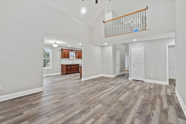 unfurnished living room featuring high vaulted ceiling and light hardwood / wood-style floors