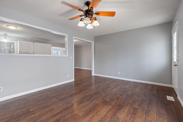 empty room featuring plenty of natural light, dark wood-type flooring, and ceiling fan