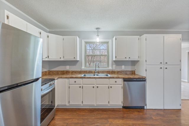 kitchen featuring stainless steel appliances, white cabinetry, sink, and decorative light fixtures