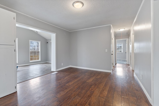 empty room featuring crown molding, vaulted ceiling, a textured ceiling, and dark hardwood / wood-style flooring