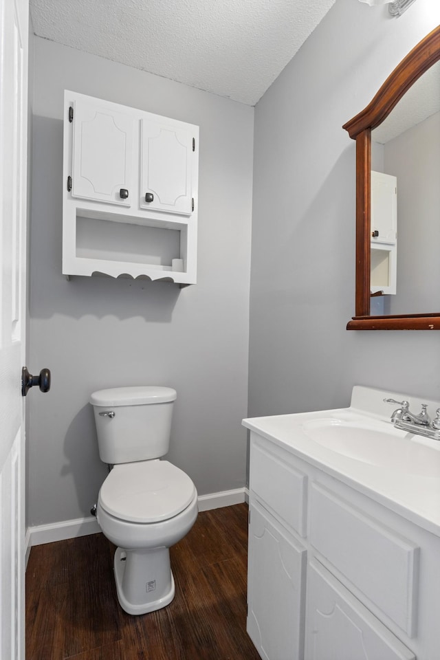 bathroom with hardwood / wood-style flooring, vanity, toilet, and a textured ceiling