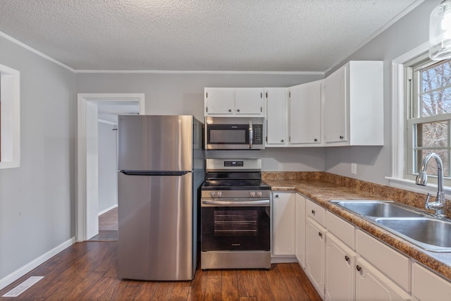 kitchen with sink, appliances with stainless steel finishes, dark hardwood / wood-style floors, ornamental molding, and white cabinets