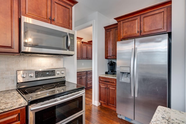 kitchen with stainless steel appliances, dark hardwood / wood-style flooring, light stone countertops, and backsplash