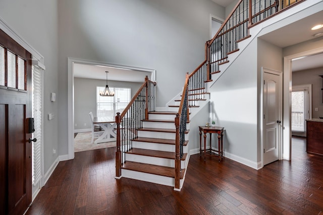 foyer entrance with a high ceiling, dark wood-type flooring, and a chandelier