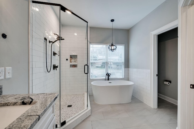 bathroom with tile patterned floors, vanity, independent shower and bath, and tile walls