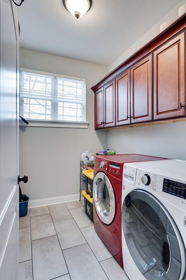 laundry area featuring light tile patterned floors, cabinets, and washing machine and clothes dryer