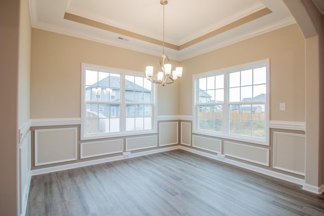 empty room featuring crown molding, hardwood / wood-style floors, a tray ceiling, and a notable chandelier