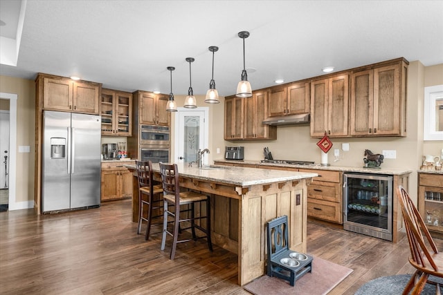 kitchen with wine cooler, sink, decorative light fixtures, a center island with sink, and appliances with stainless steel finishes