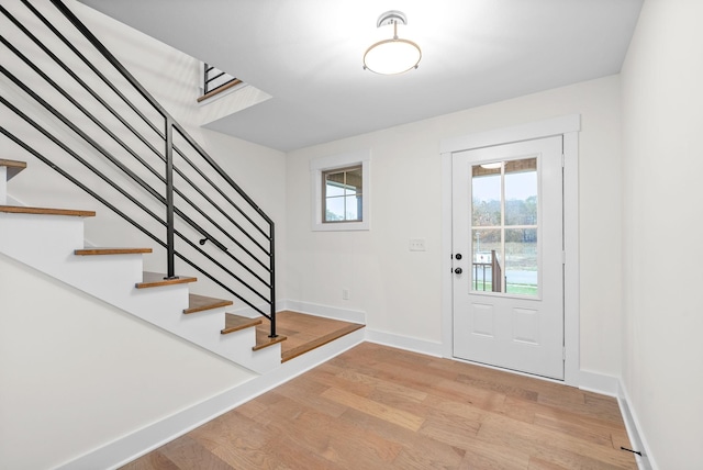 entrance foyer featuring light wood-style floors, baseboards, and stairs