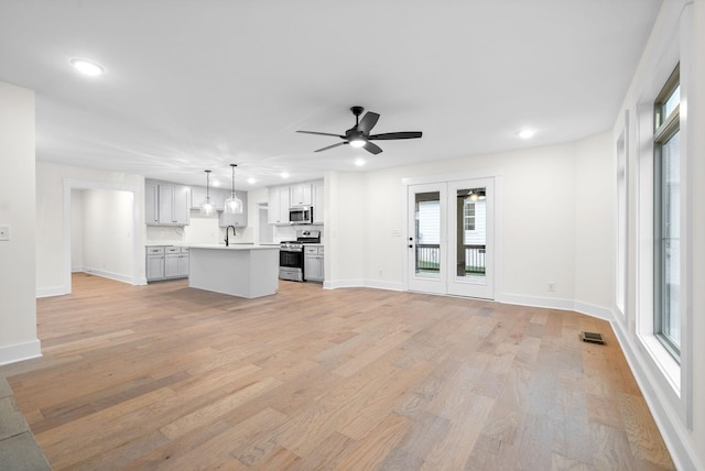 unfurnished living room with light wood-type flooring, baseboards, a ceiling fan, and recessed lighting