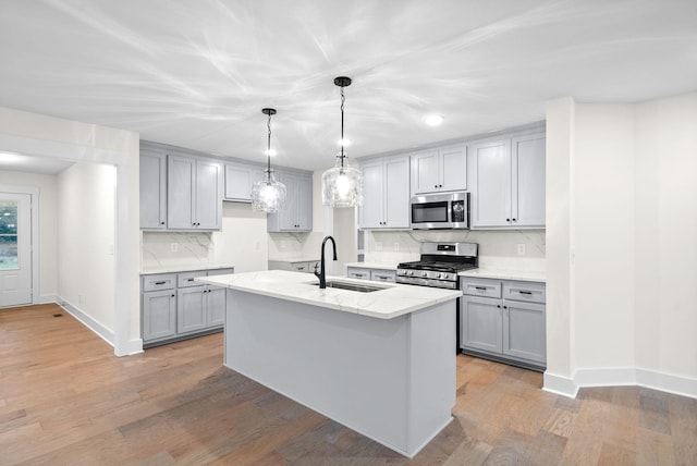 kitchen with stainless steel appliances, light wood-style floors, gray cabinets, and a sink