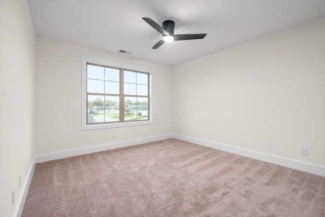 carpeted empty room featuring ceiling fan, visible vents, and baseboards