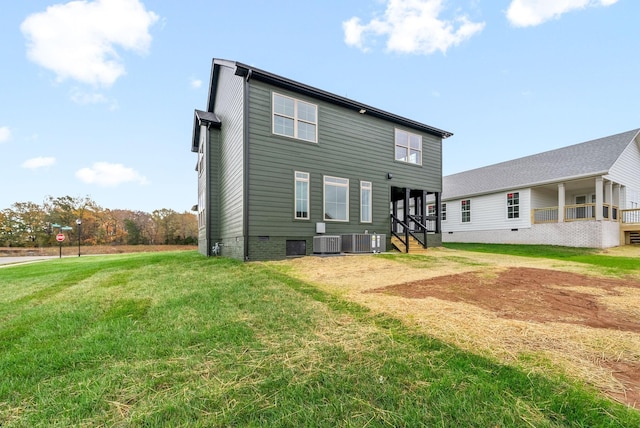 back of property with crawl space, central AC, and a yard