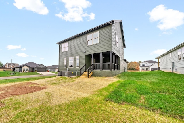 rear view of property featuring central AC and a lawn