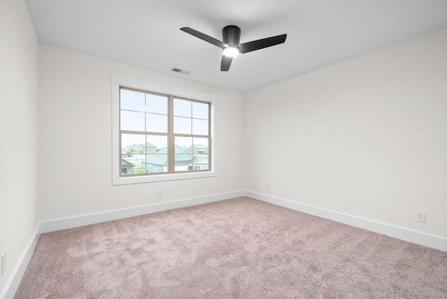 empty room featuring carpet floors, visible vents, baseboards, and a ceiling fan