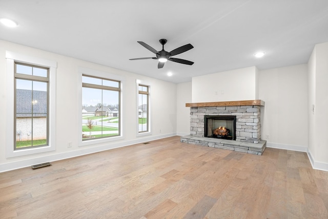 unfurnished living room featuring baseboards, a fireplace, visible vents, and wood finished floors