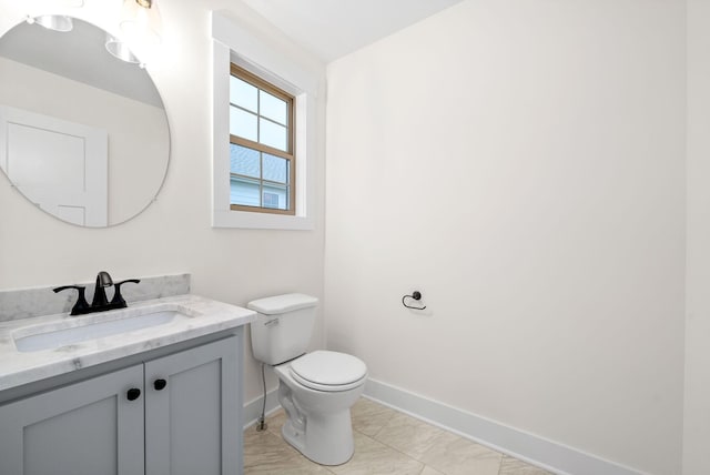 bathroom featuring toilet, baseboards, and vanity