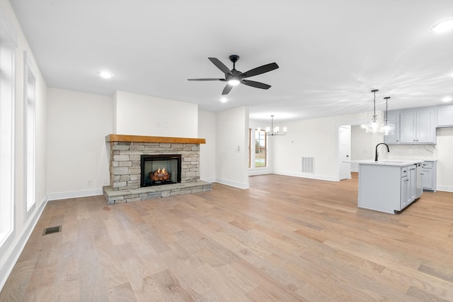 unfurnished living room with light wood finished floors, a fireplace, a sink, and visible vents