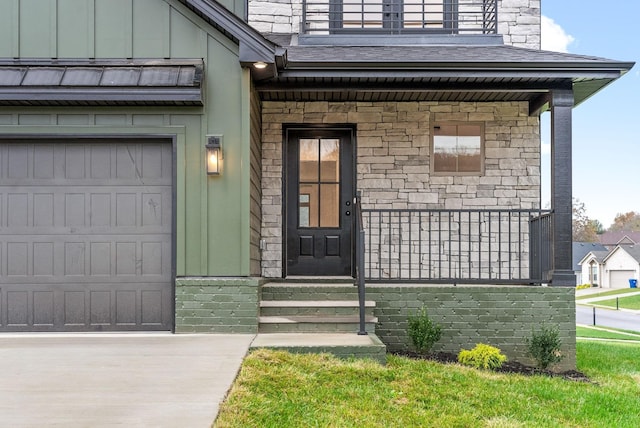 entrance to property with a balcony, stone siding, an attached garage, a porch, and board and batten siding