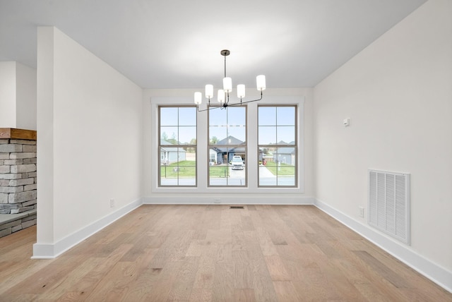 unfurnished dining area featuring an inviting chandelier, baseboards, visible vents, and light wood finished floors