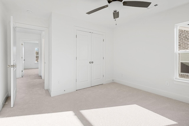 unfurnished bedroom with light carpet, ceiling fan, and a closet