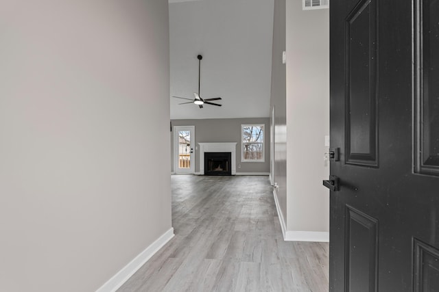 foyer entrance with a high ceiling, ceiling fan, and light wood-type flooring