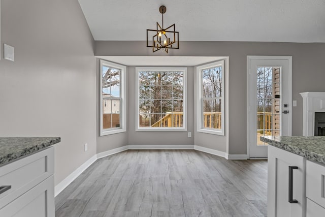 unfurnished dining area featuring vaulted ceiling, light hardwood / wood-style flooring, and a notable chandelier