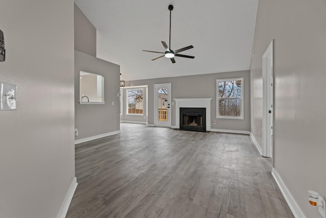 unfurnished living room with ceiling fan, wood-type flooring, and vaulted ceiling