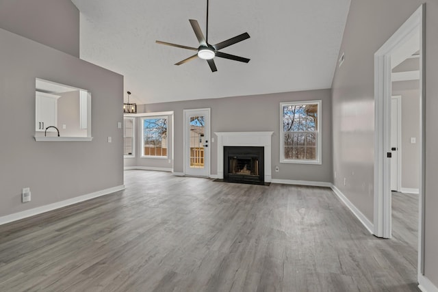 unfurnished living room with ceiling fan, lofted ceiling, light hardwood / wood-style flooring, and a textured ceiling